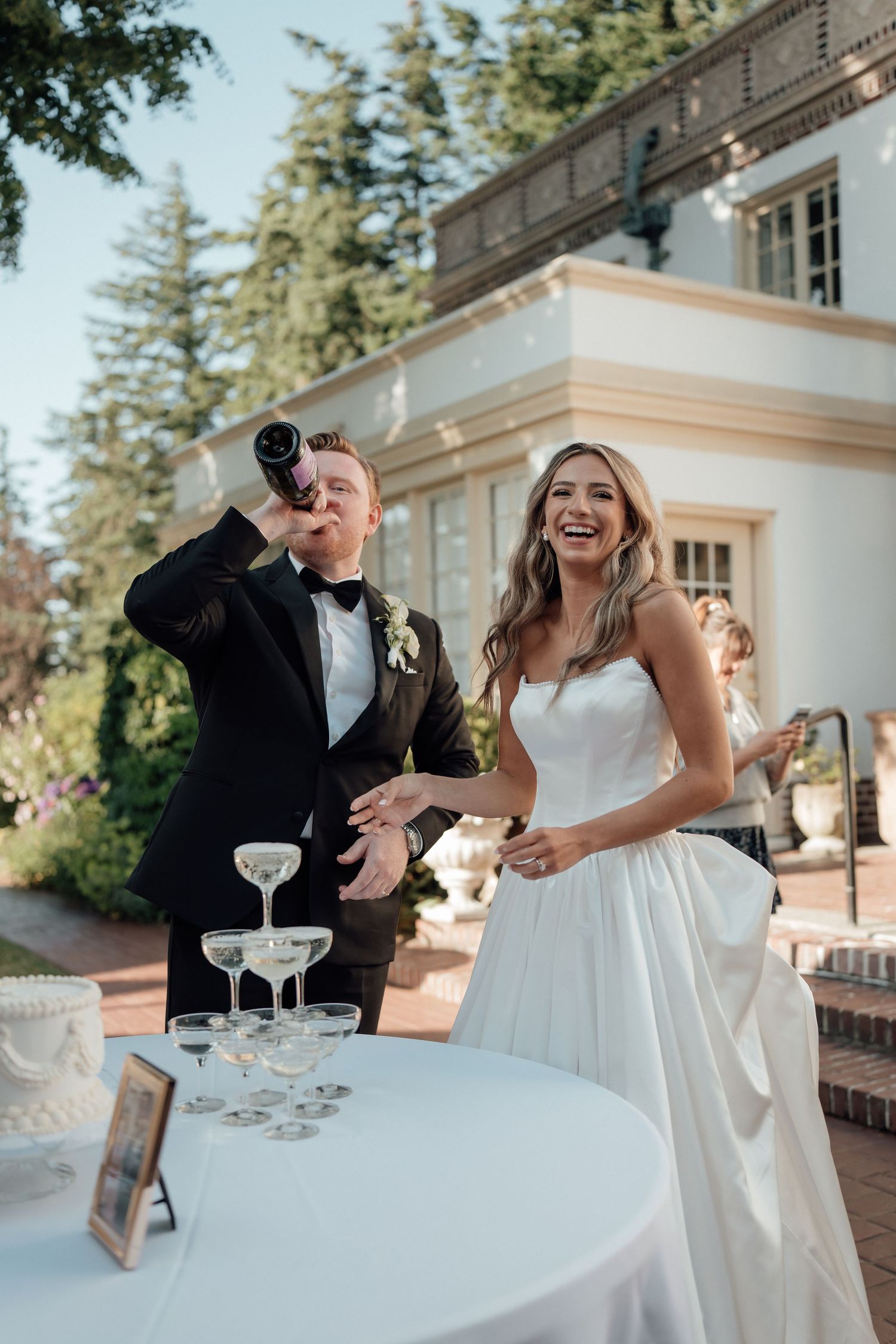 A joyful wedding celebration moment with champagne at an outdoor table.