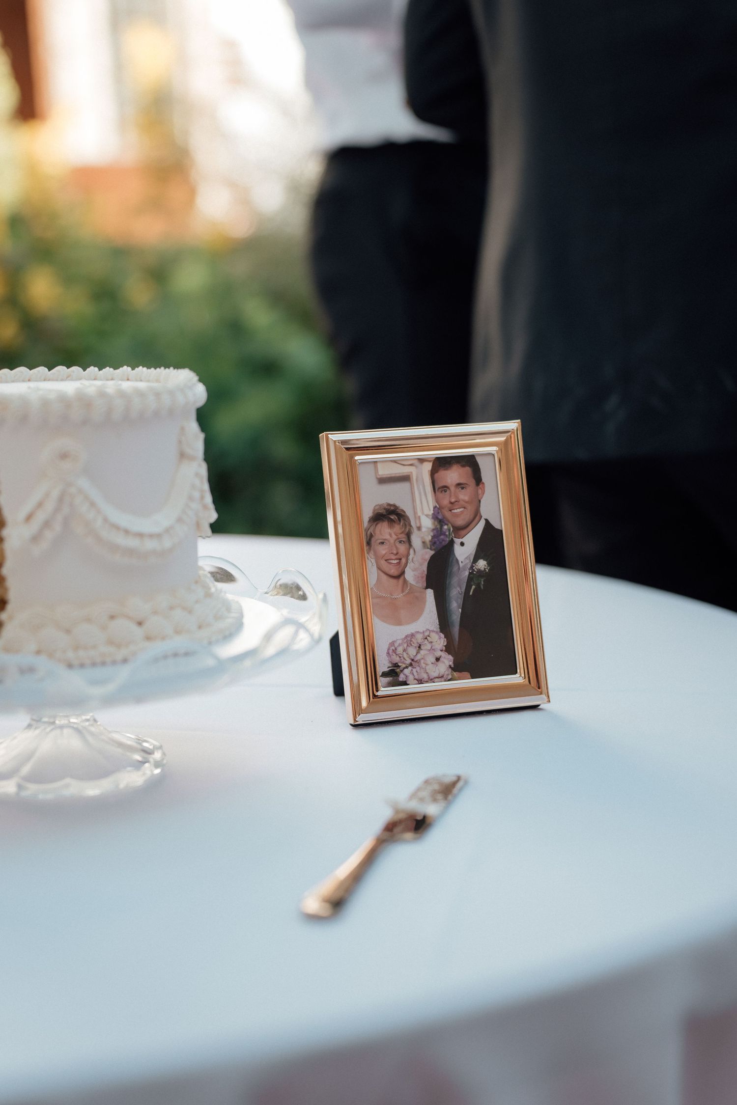 Framed wedding photos and decorative elements displayed on a white tablecloth at a reception.