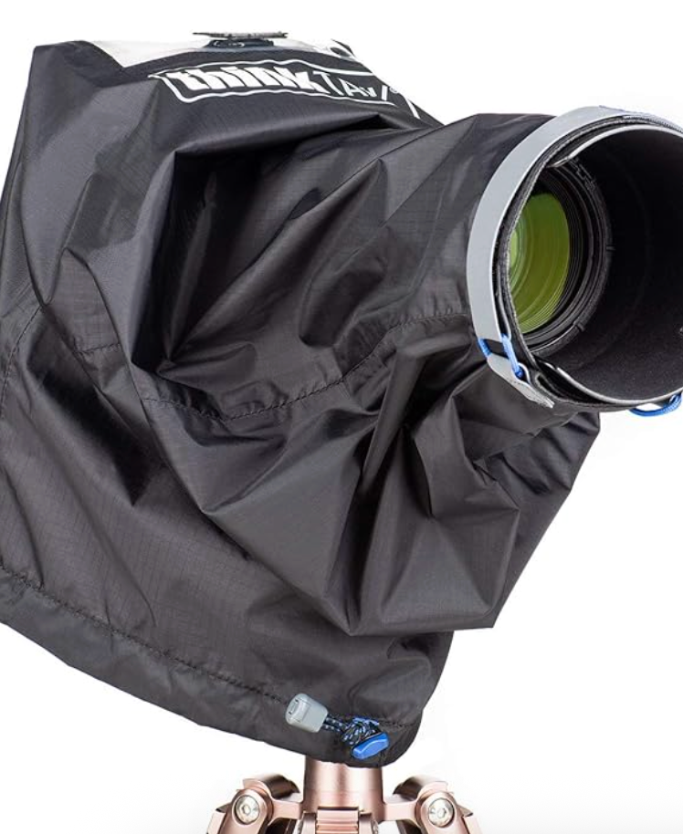Black weather-resistant camera rain cover protecting a large telephoto lens mounted on a tripod.