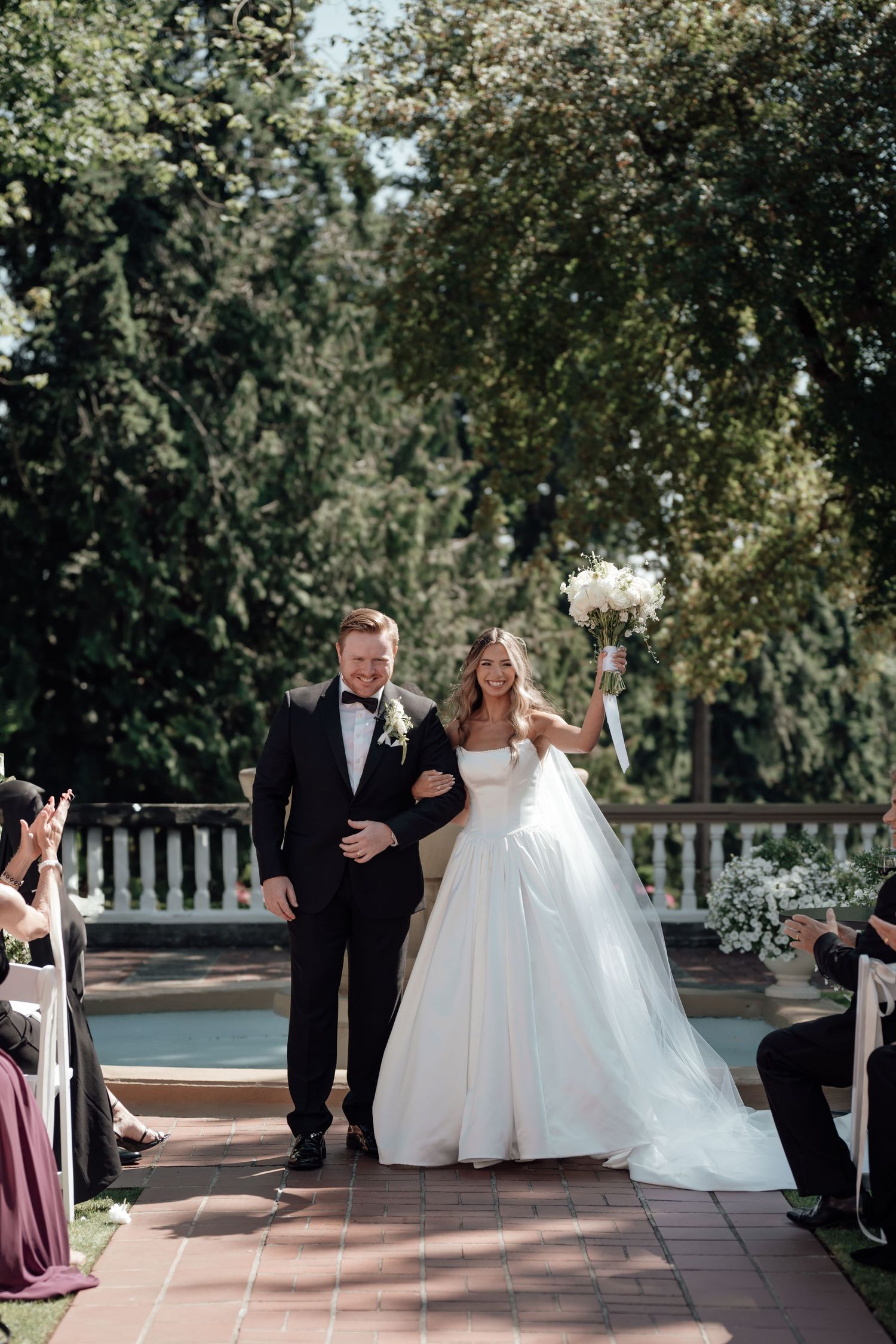 Couple walking down outdoor aisle during garden wedding ceremony.