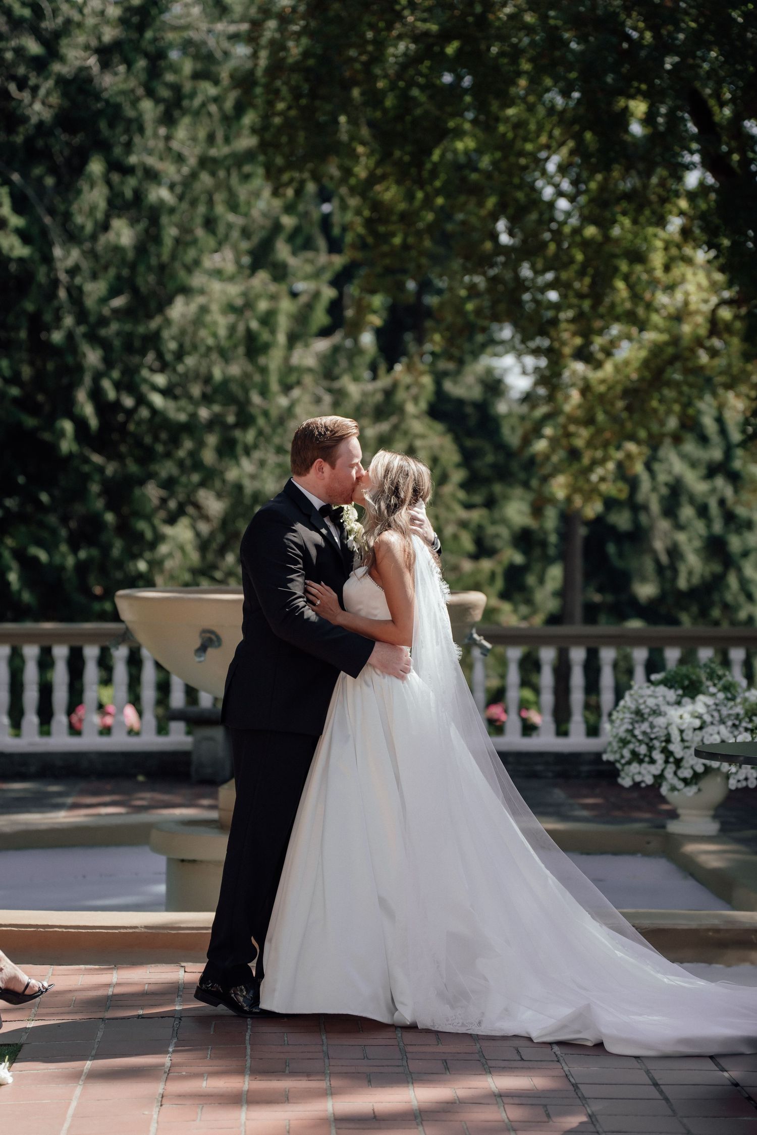 Wedding couple sharing an intimate moment on a brick terrace surrounded by greenery.