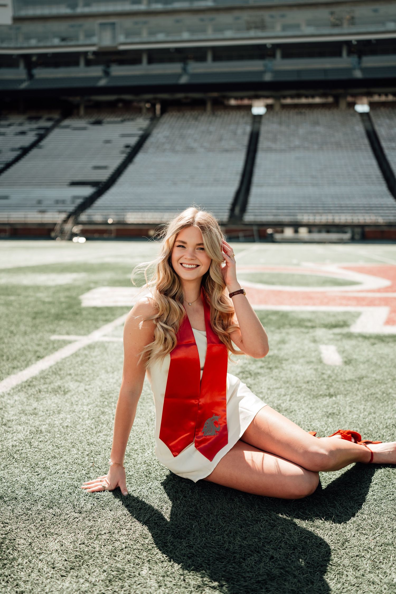 A person in a red and white outfit poses on a football field in multiple athletic poses beneath bright sunlight.