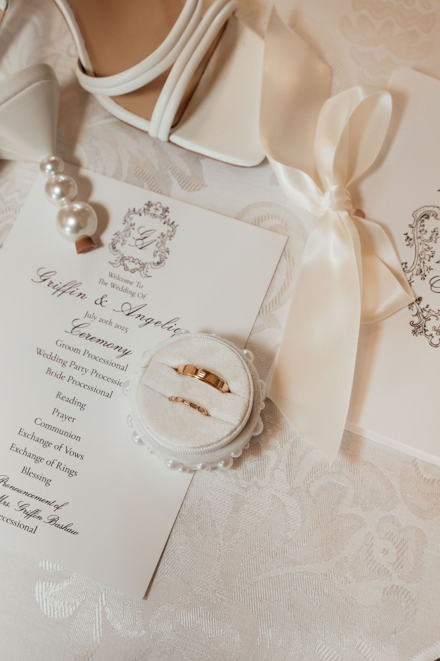 Elegant white wedding invitations with delicate ribbon and decorative details on textured fabric.