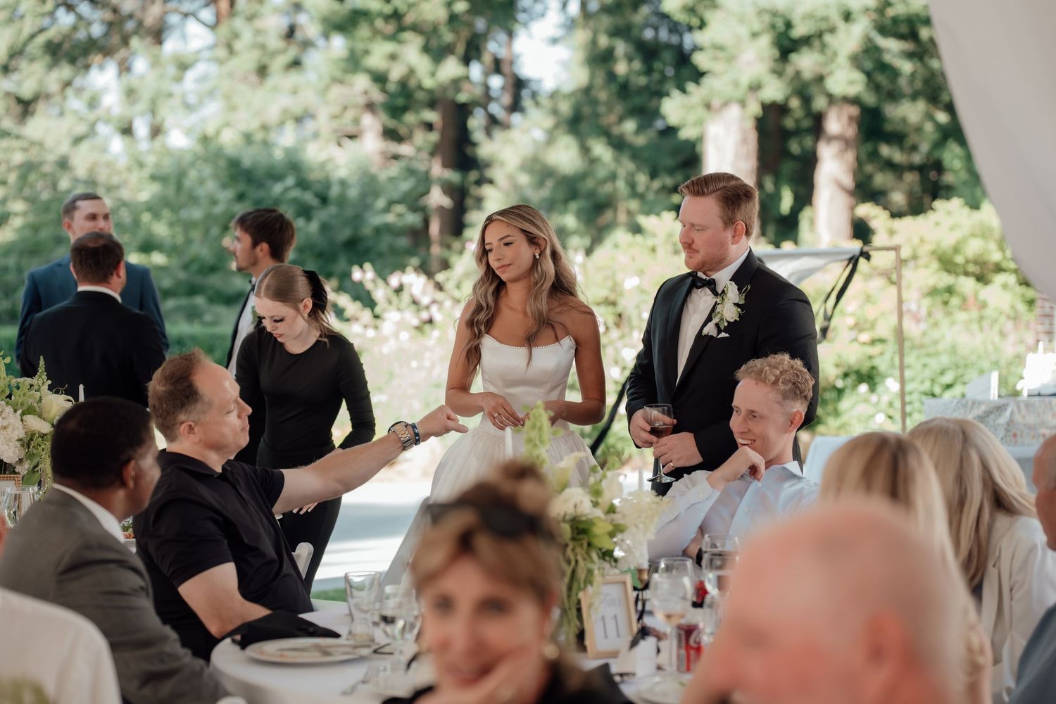 Wedding reception outdoors with guests seated at decorated tables.