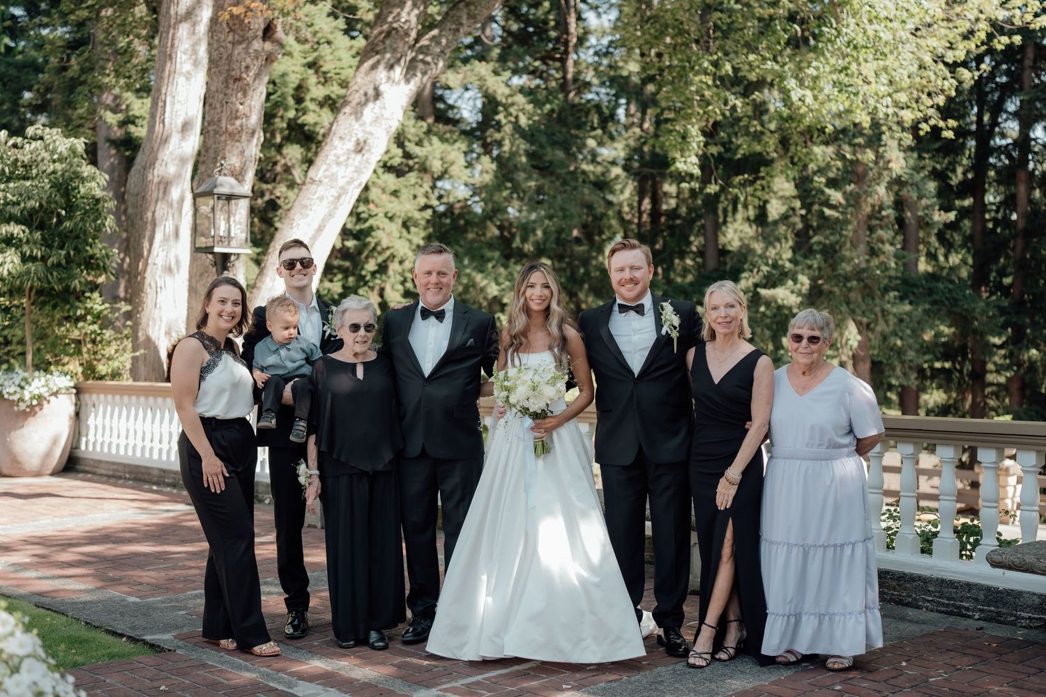 Wedding party poses together on outdoor terrace surrounded by trees.