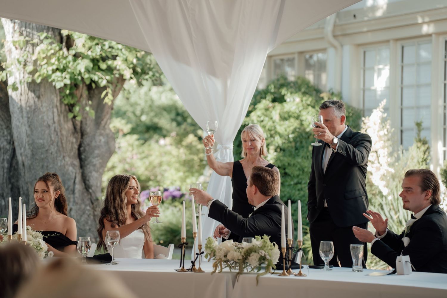 Wedding reception under an elegant white tent with tables and guests gathered for celebration.