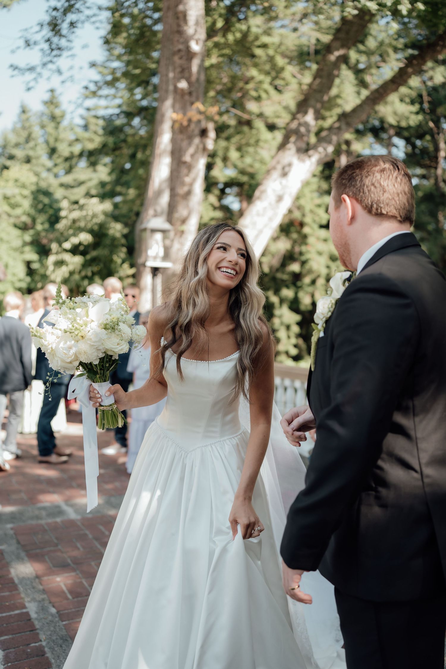 A couple shares a joyful moment on a brick pathway during their outdoor wedding.