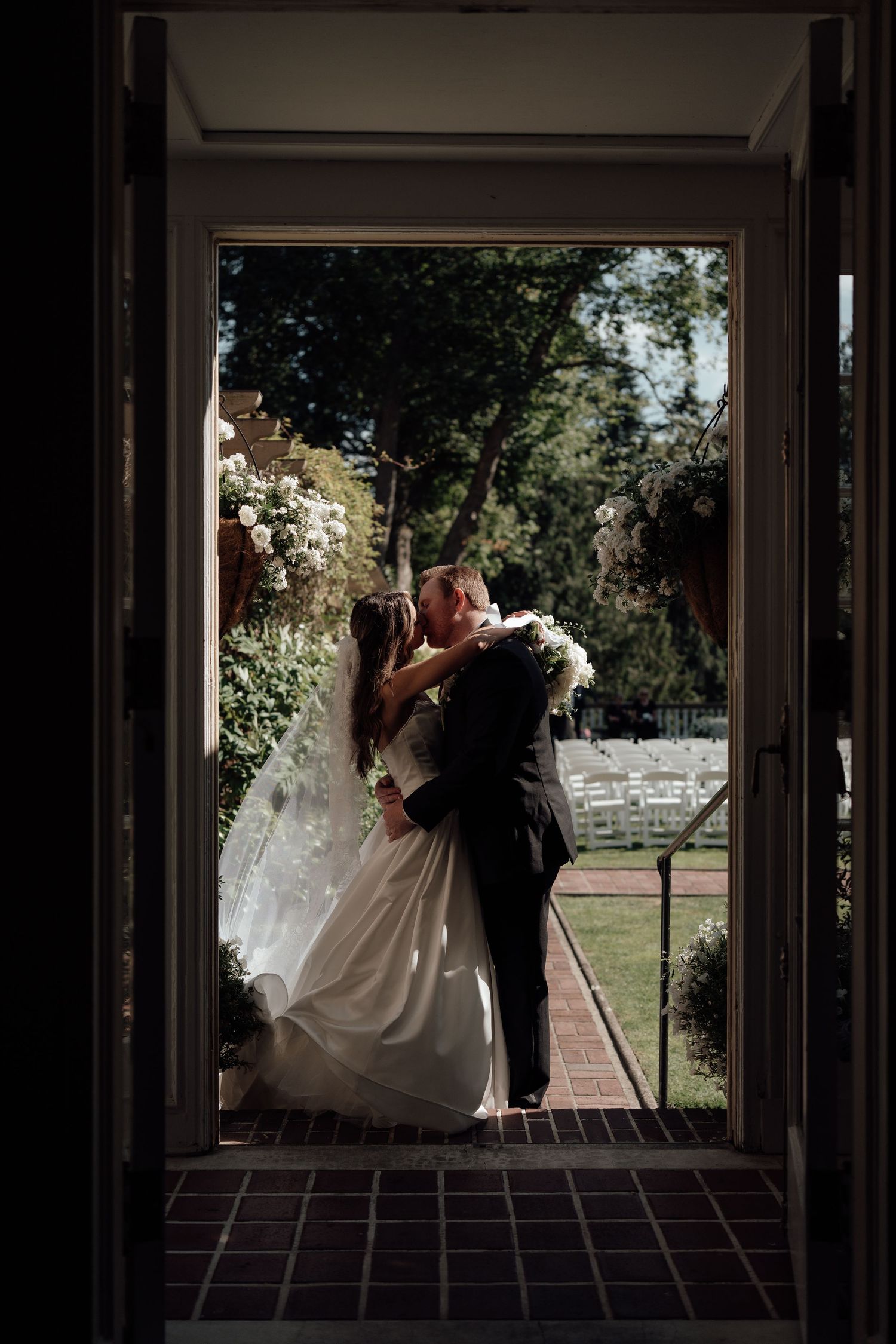 Romantic silhouettes of a bride and groom embracing through a series of window frames at golden hour.