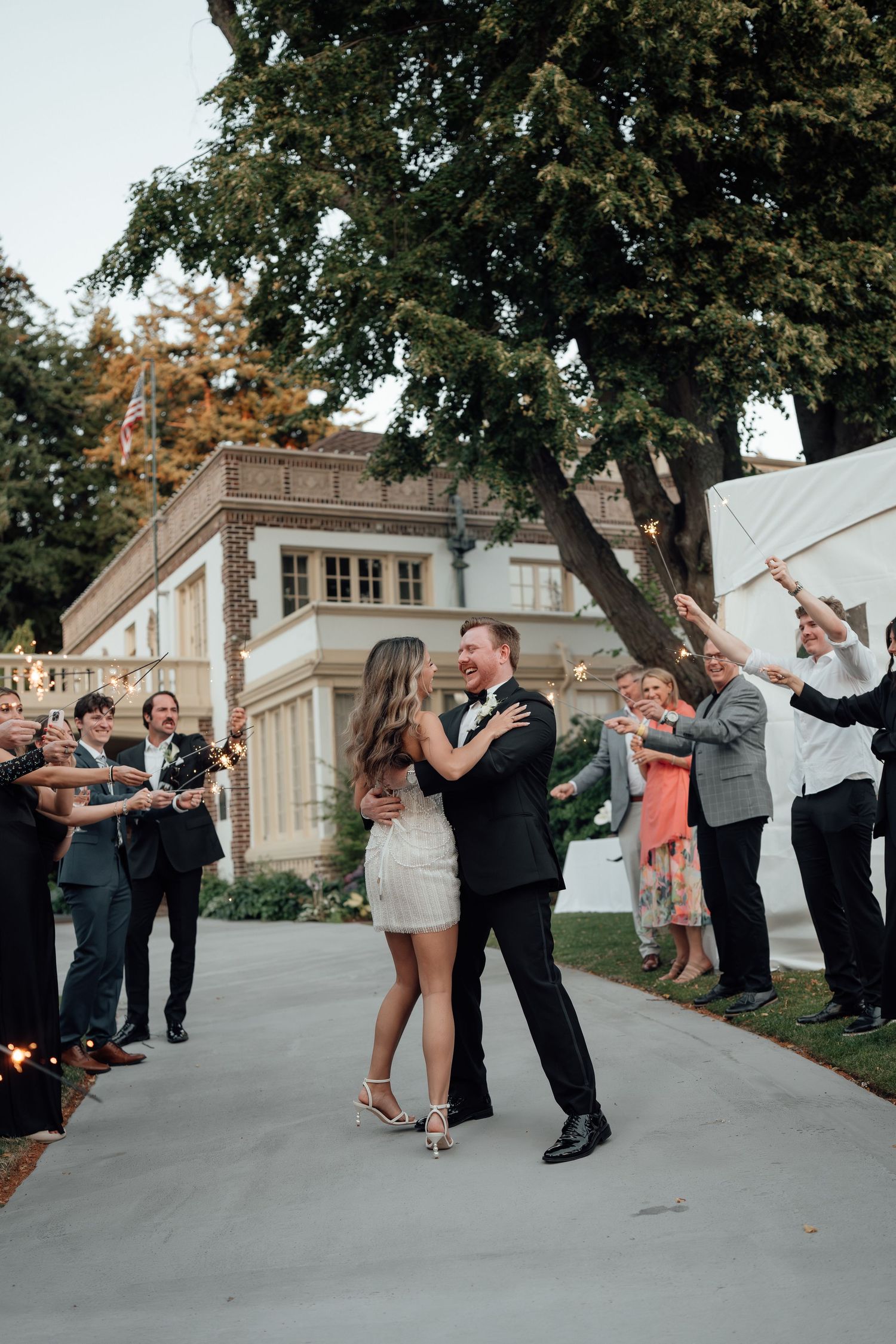 Wedding celebration dance sequence on outdoor pavement with guests joining in the festivities.