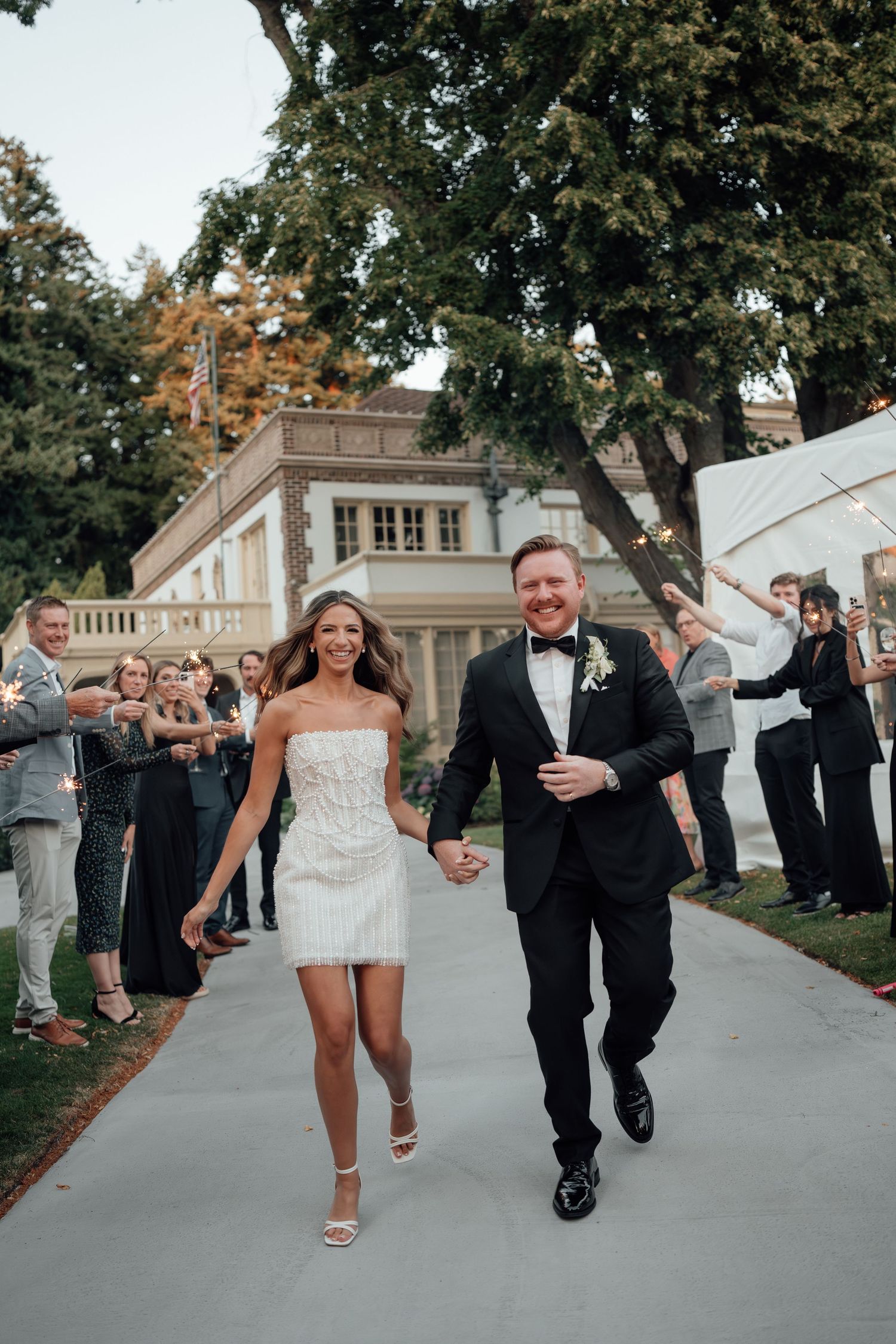 A celebratory moment as newlyweds run down a path while guests cheer.