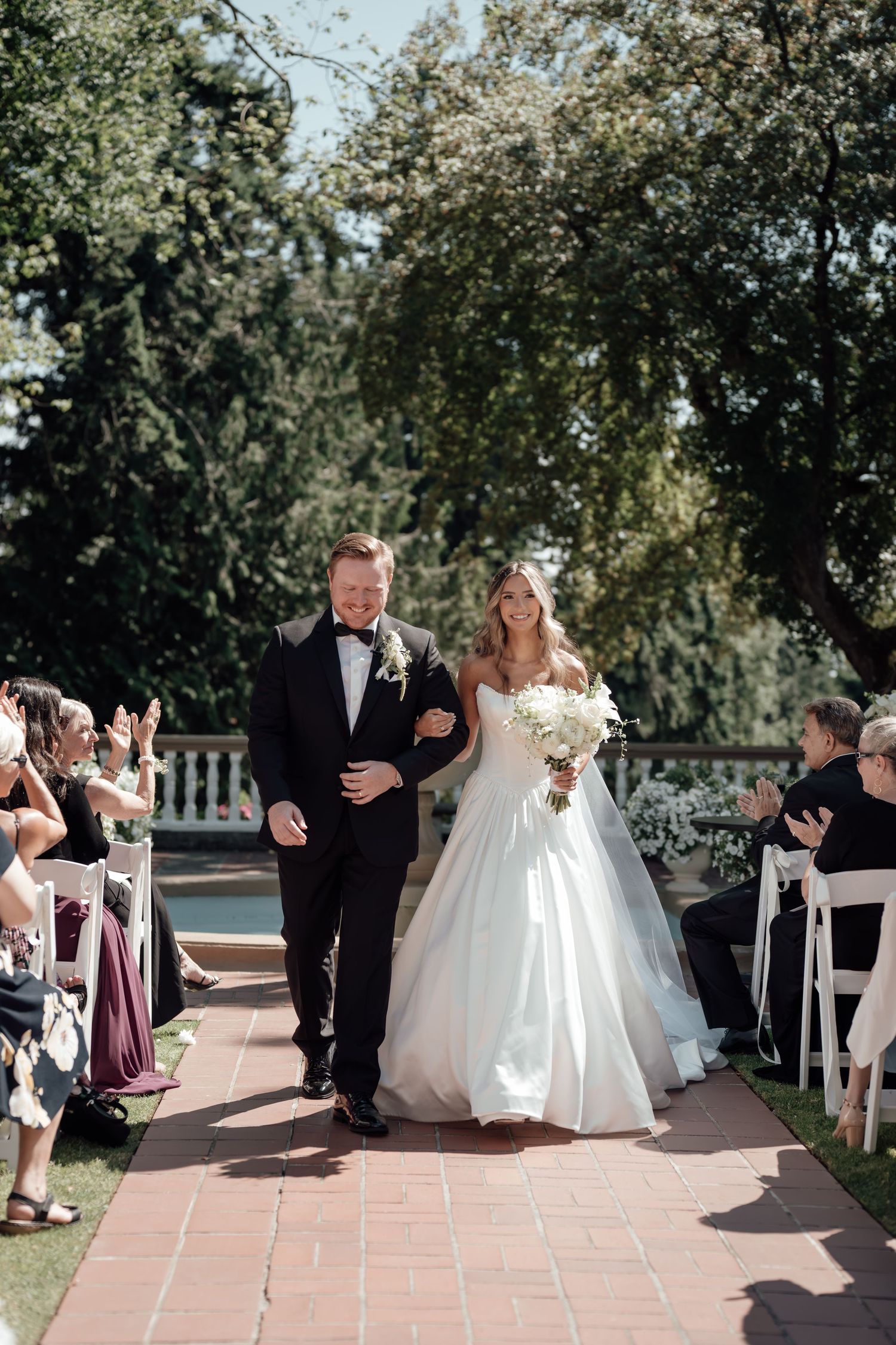 Wedding ceremony at an outdoor venue with guests seated and a walkway for the bridal party.