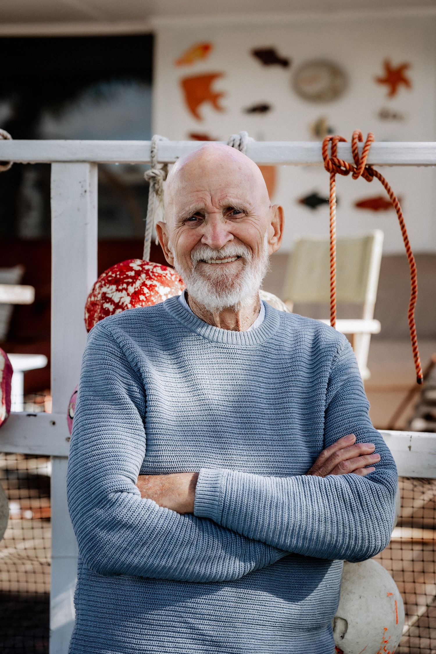 A portrait of an elderly man with his arms crossed, looking directly at the camera.