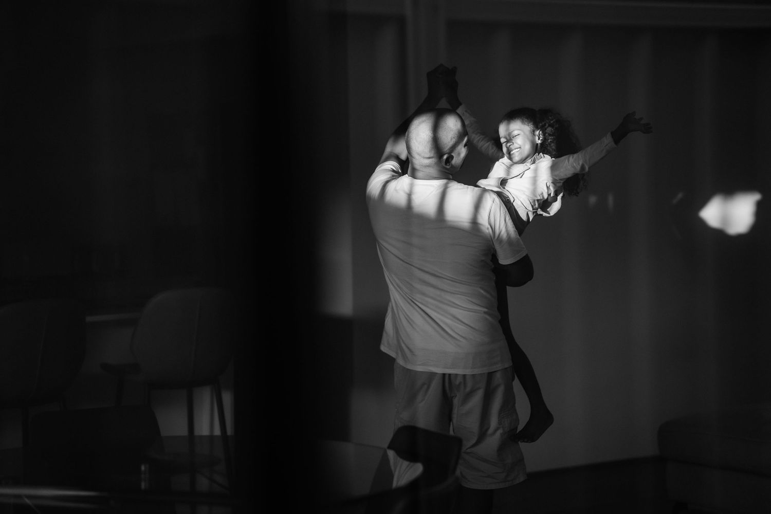 A South African Dad and her young daughter, dancing in a patch of sunlight in their lounge room