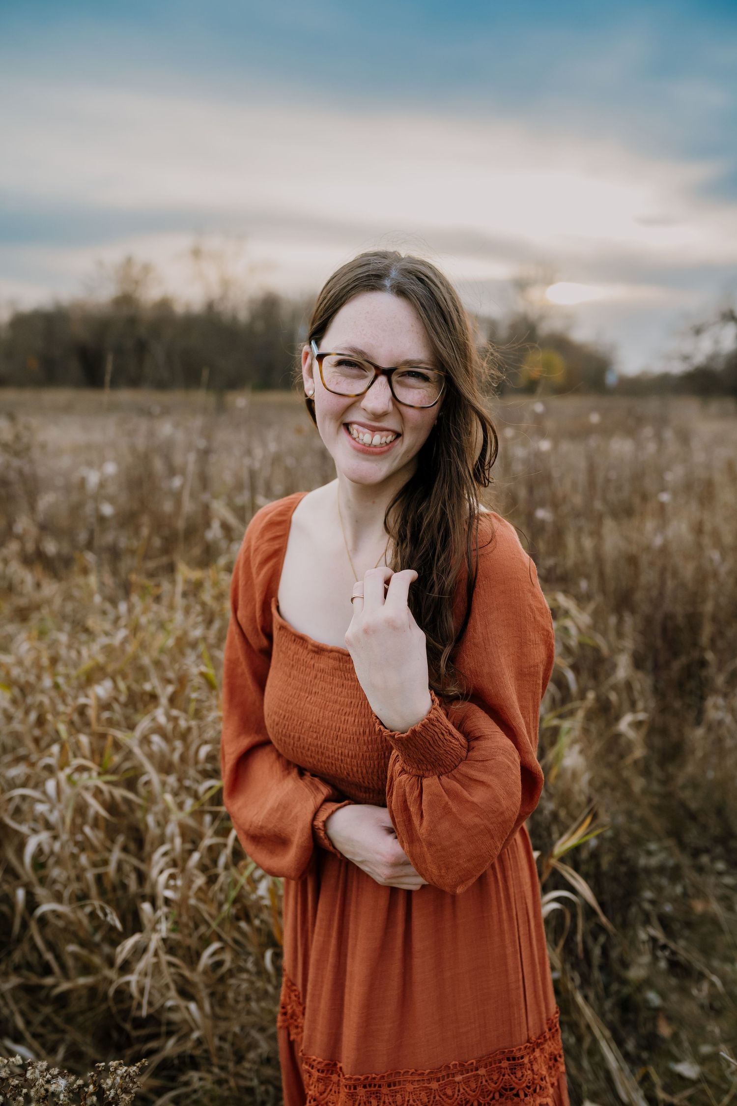 Woman stands in a field and smiles