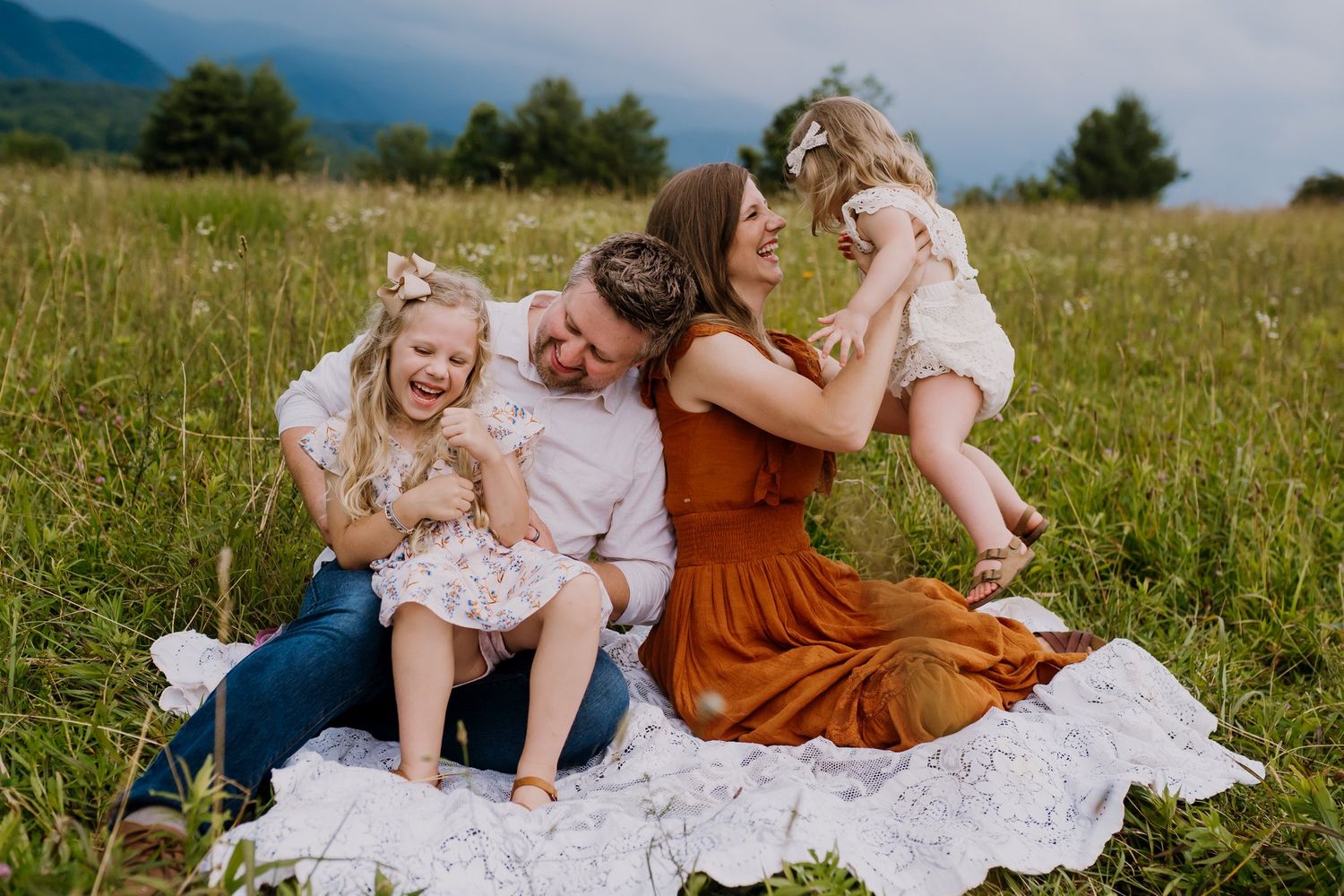 Family plays a game on a blanket during family photos in Cades Cove