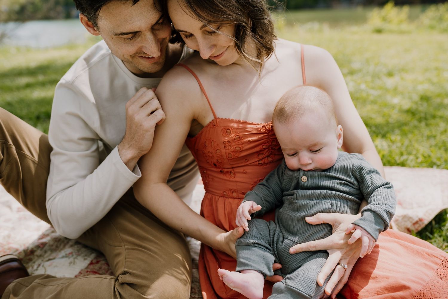 Parents sit on picnic blanket and play with their baby