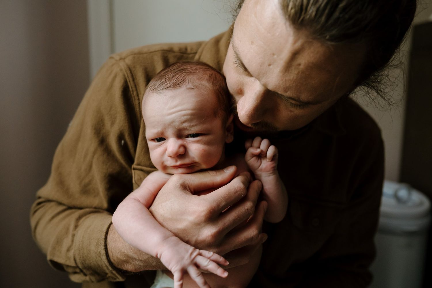 Newborn baby in dad's hands as dad shushes him
