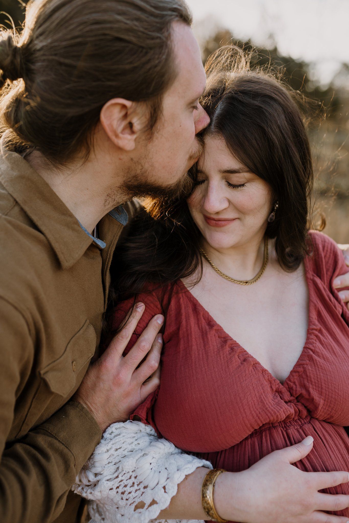 Dad embraces and kisses mom during maternity photos