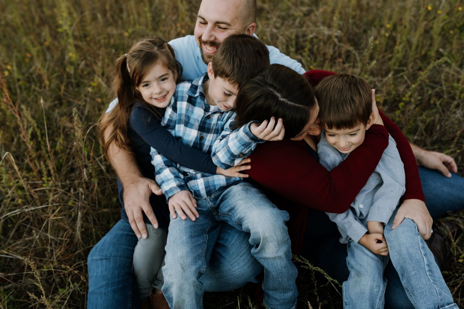 Family snuggles in the grass together