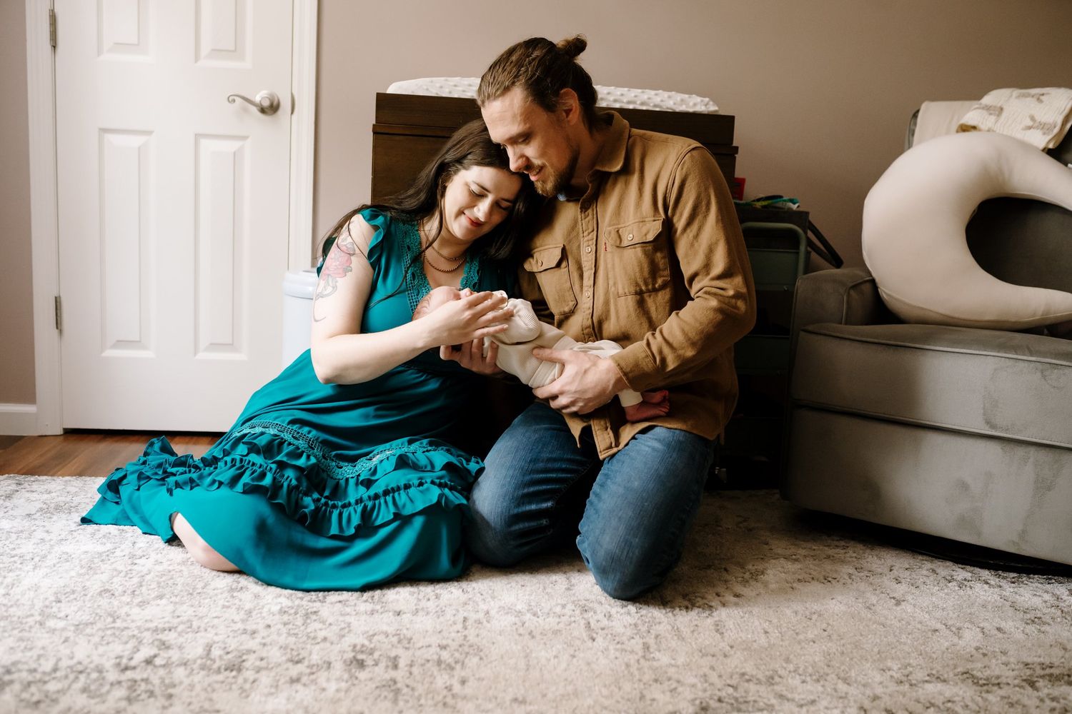 Mom and dad sit on nursery floor holding their newborn baby during newborn photos knoxville tn