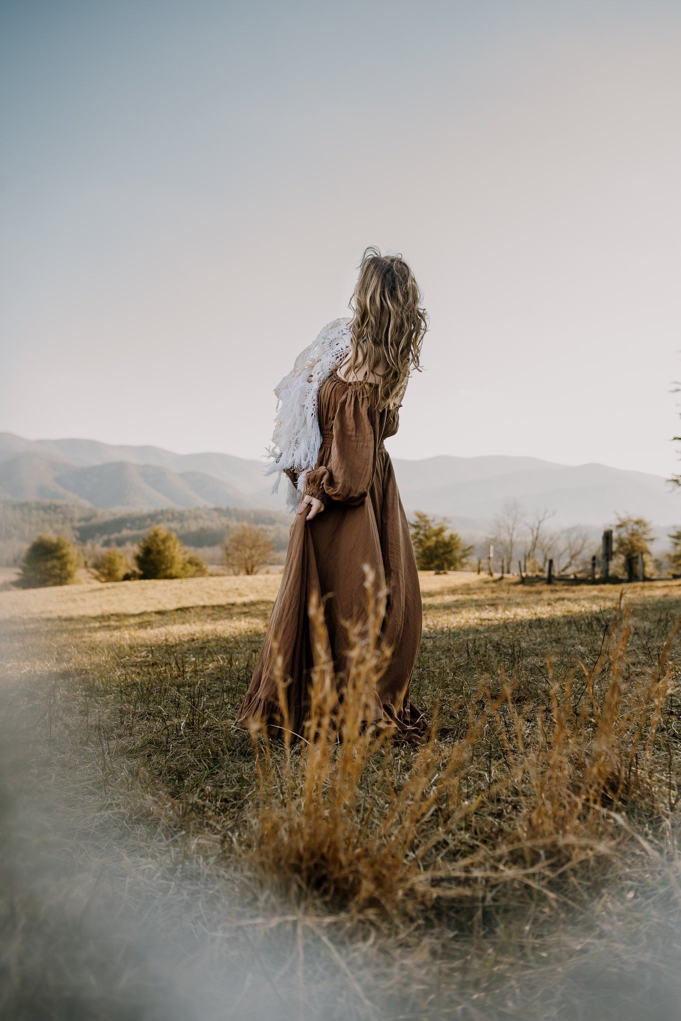 Mom wears Reclamation dress and looks toward mountains while holding baby girl