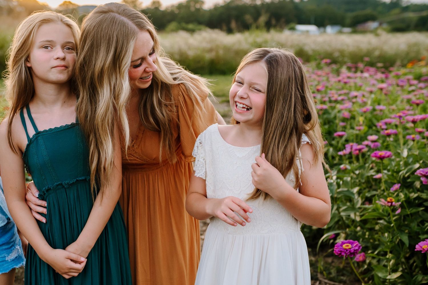 Mom smiles at her daughter as they laugh together in a zinnia field