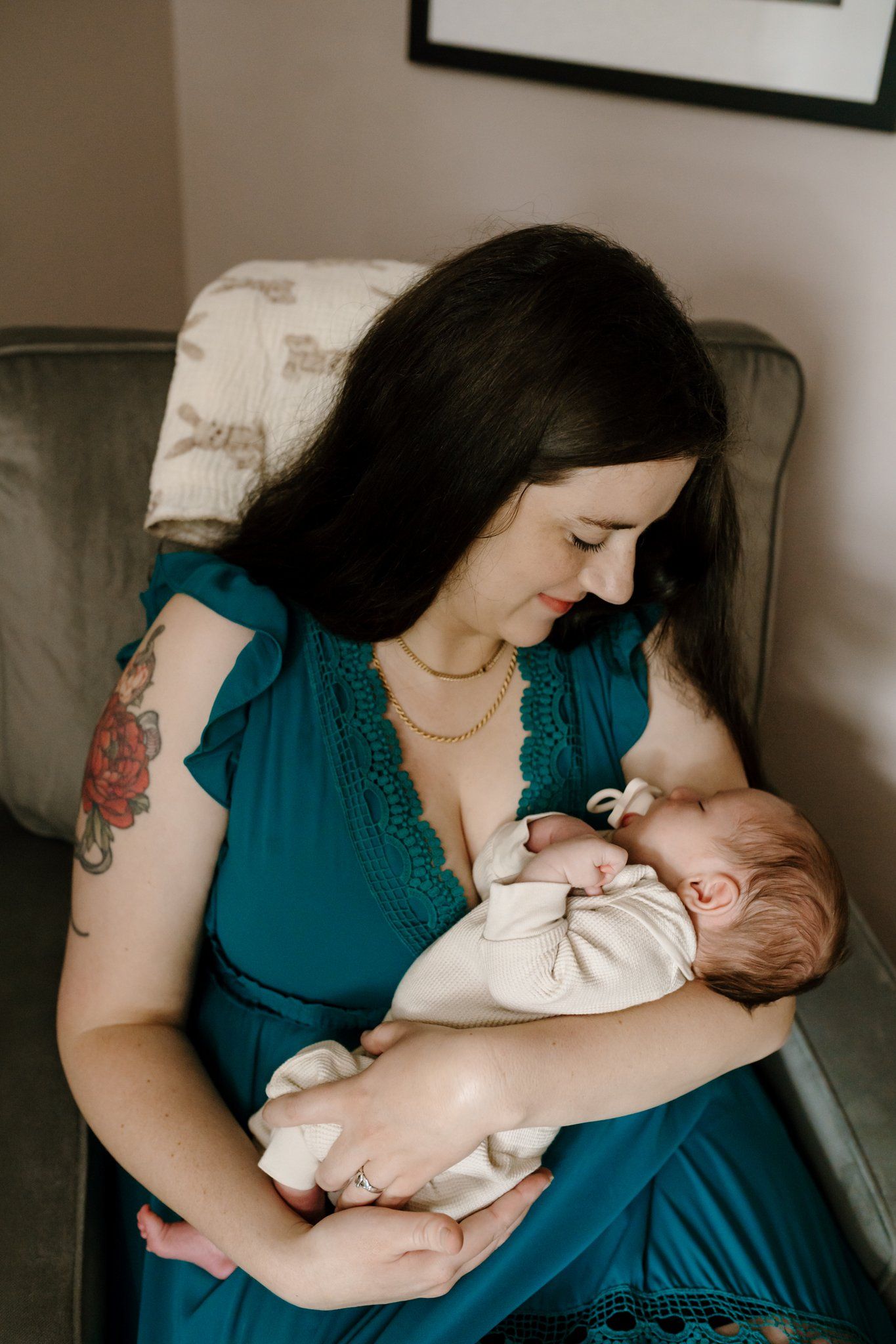 Mom gazes down at newborn while sitting in nursery chair