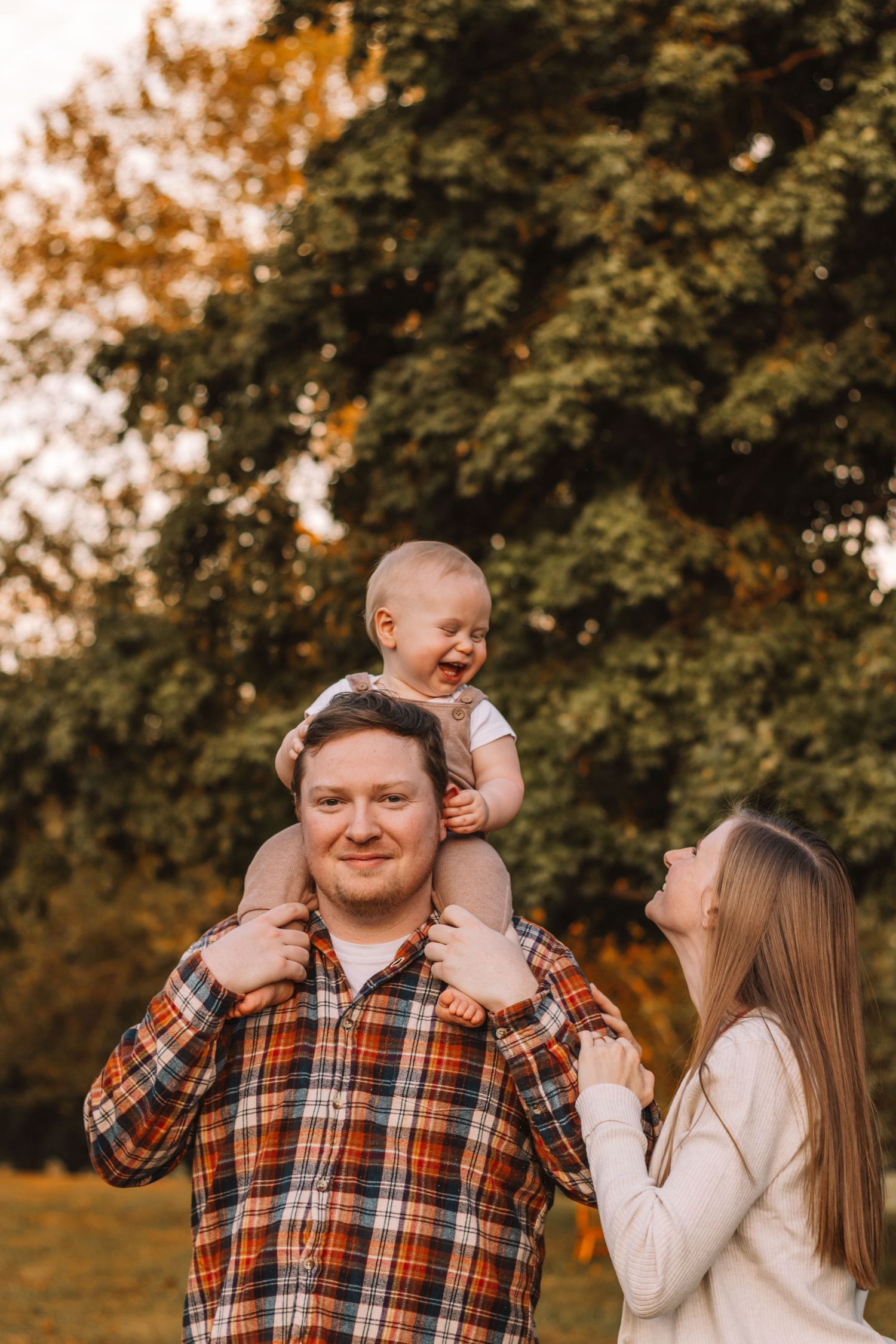 family with their one year old son on his birthday laughing at the park