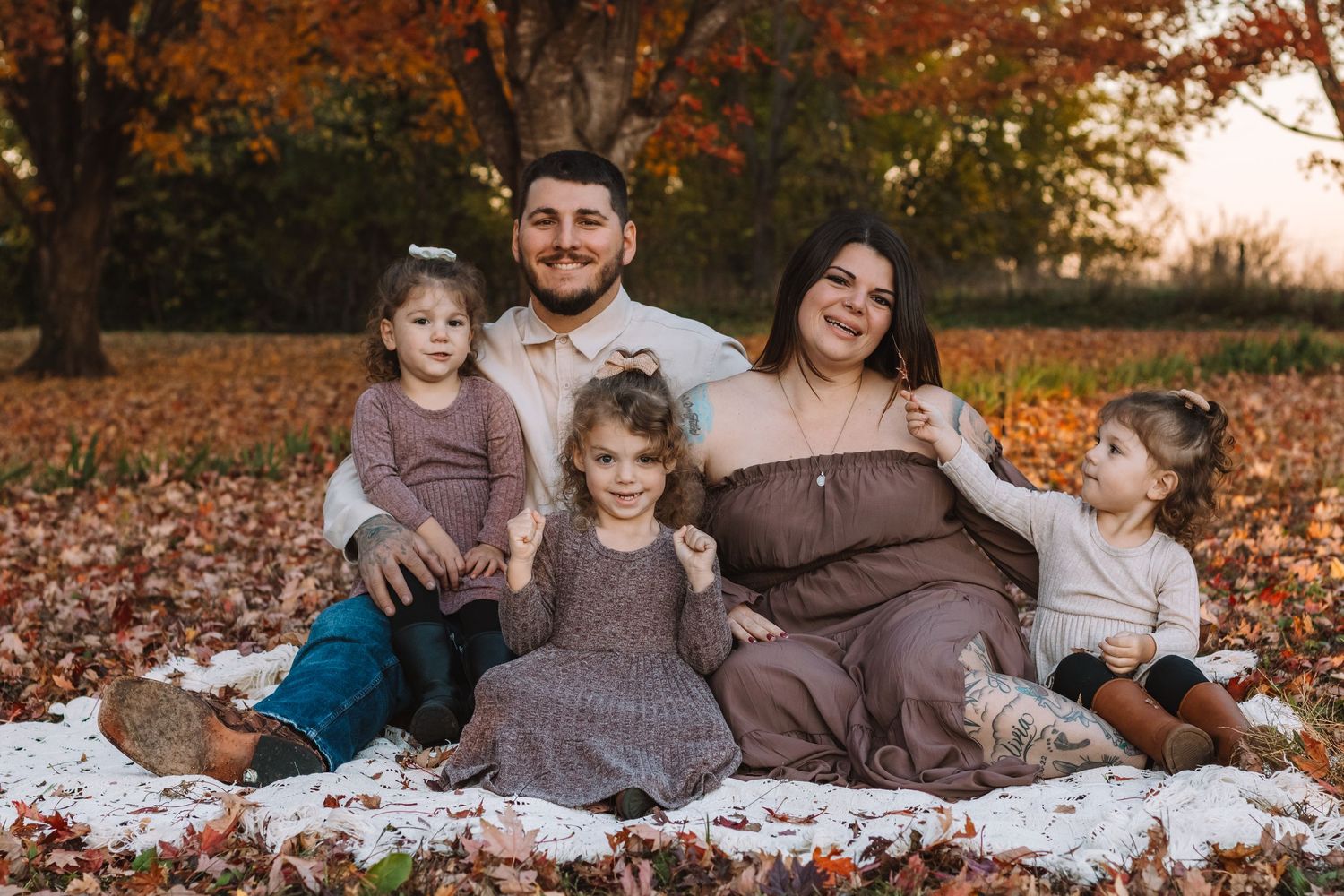 family posed on a blanket in the fall