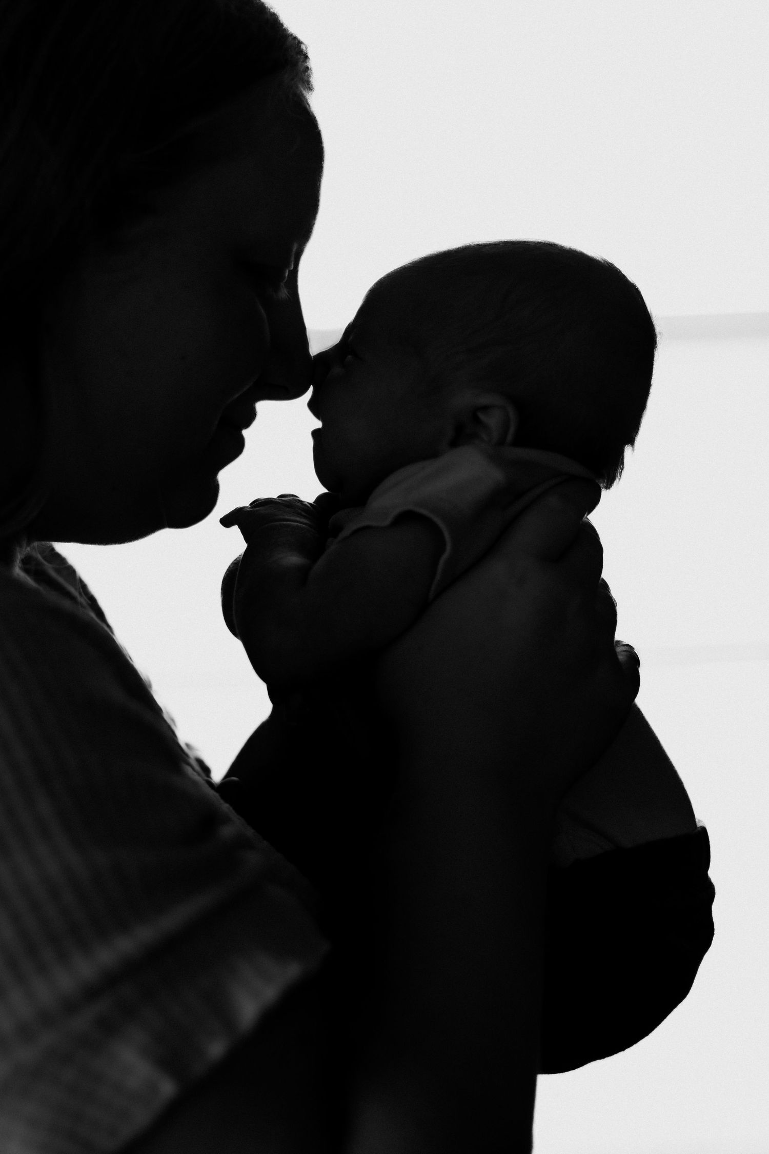 Silhouette of mother with her newborn baby in home lifestyle newborn session