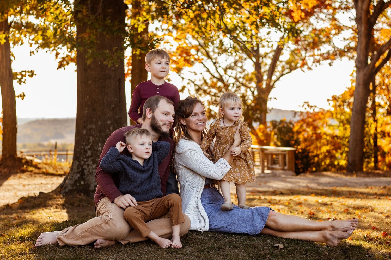 family with kids sitting in the grass at sunset
