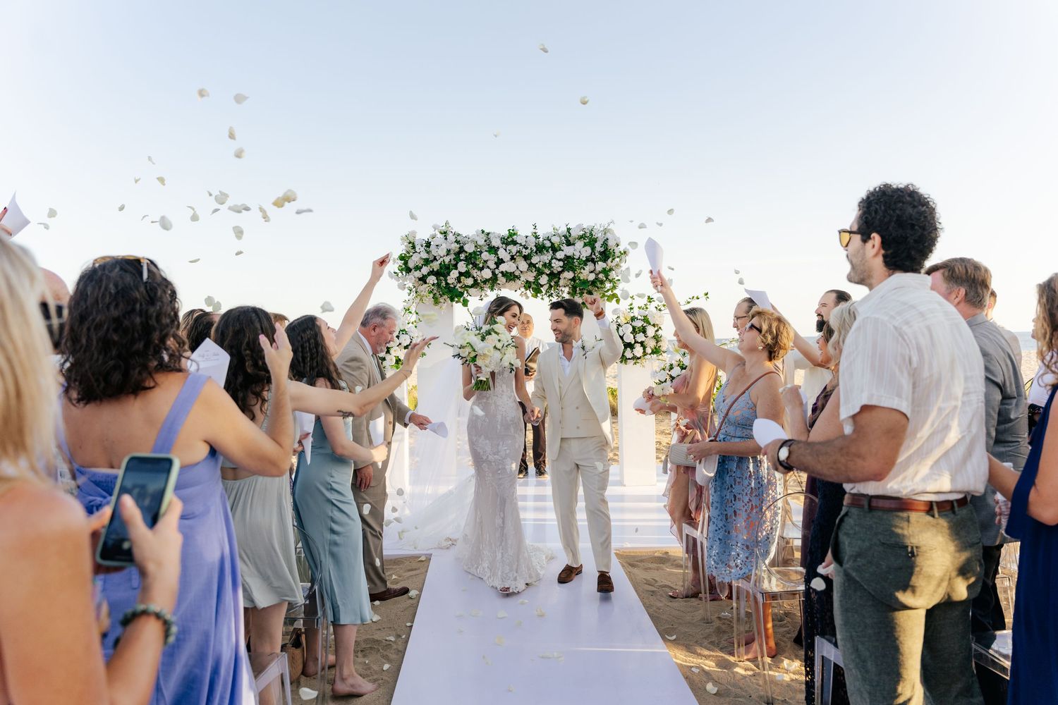 Wedding guests dance and celebrate on an outdoor dance floor during a sunset reception party.