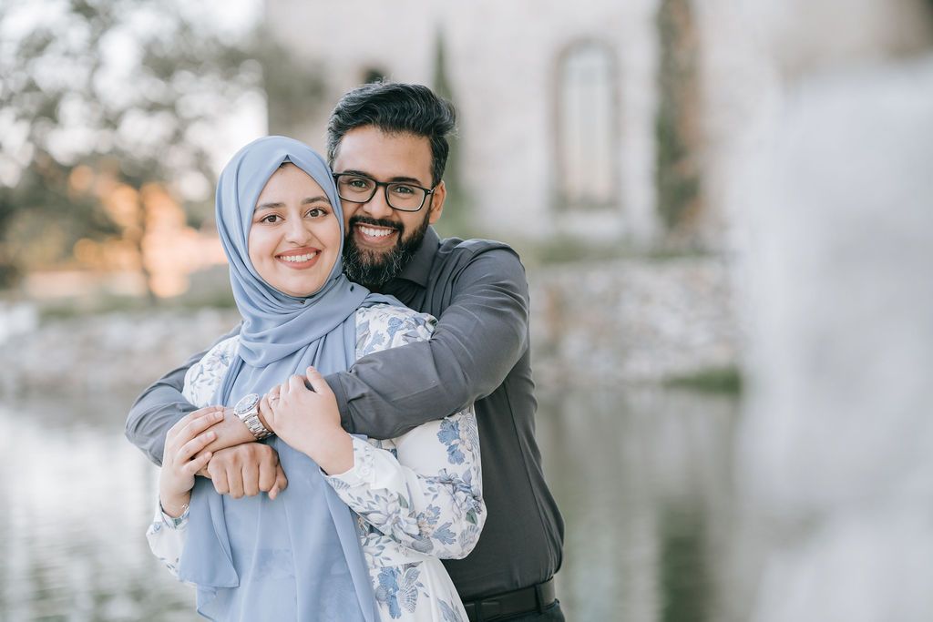 Loving couple sharing tender moment outside while embracing, with soft lighting and architectural background.
