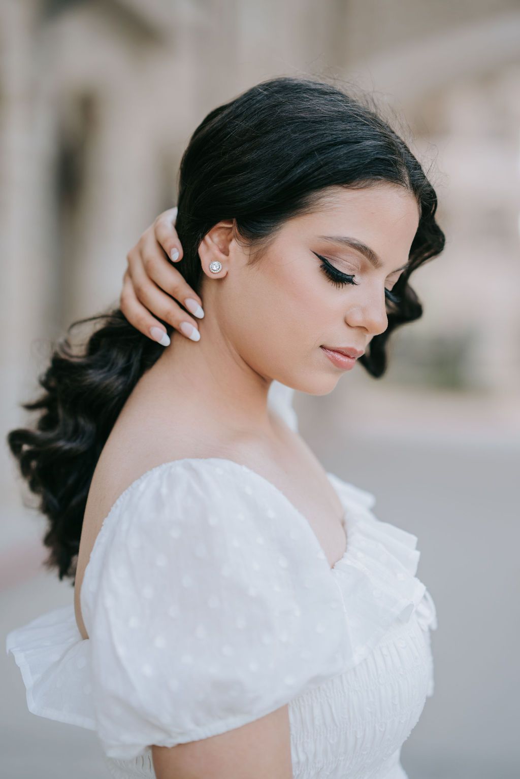 Close-up portrait showing elegant hairstyle and white dress details.