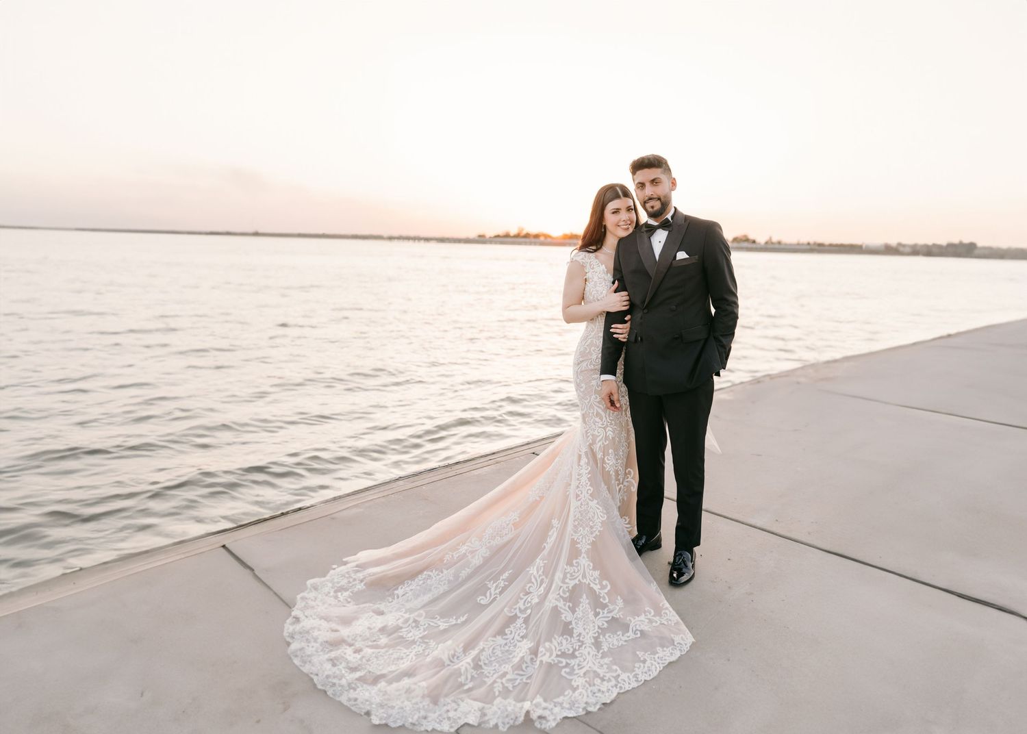 Beautiful Dallas bride and groom standing on a dock with an ocean backdrop during sunset.