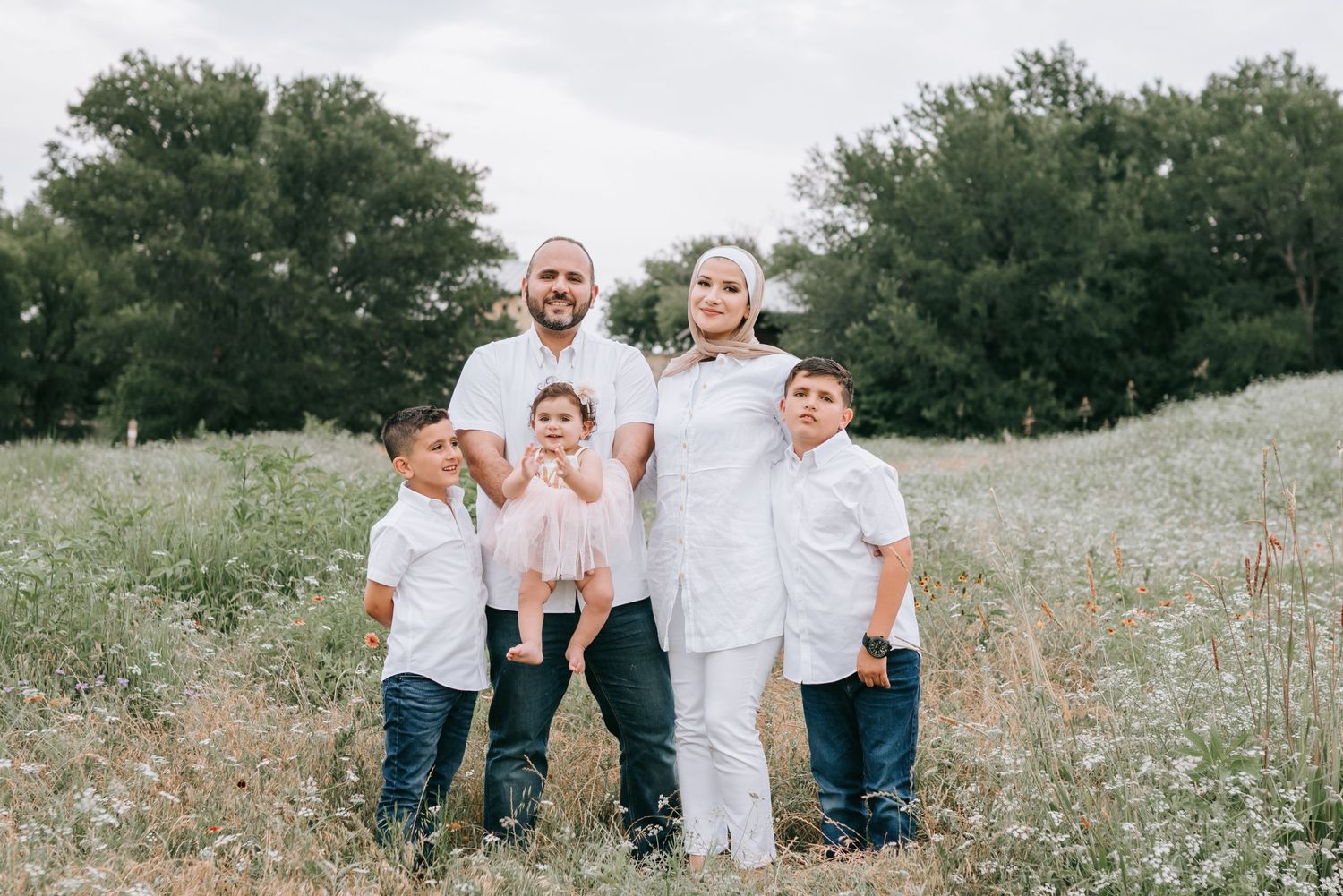 Family in Dallas standing in scenic field with greenery.