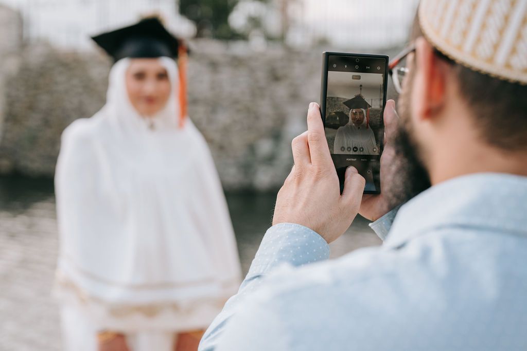 Someone taking graduation photos with smartphone in outdoor setting.