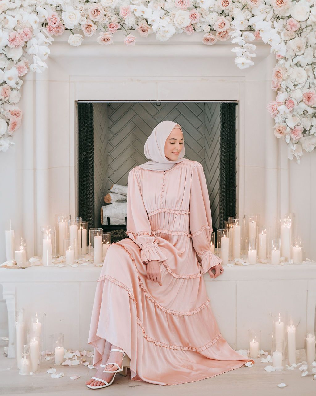 Elegant pink dress captured in romantic setting with floral arch and candles.