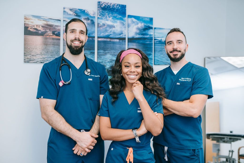 Healthcare team in matching navy scrubs posing together in medical office.
