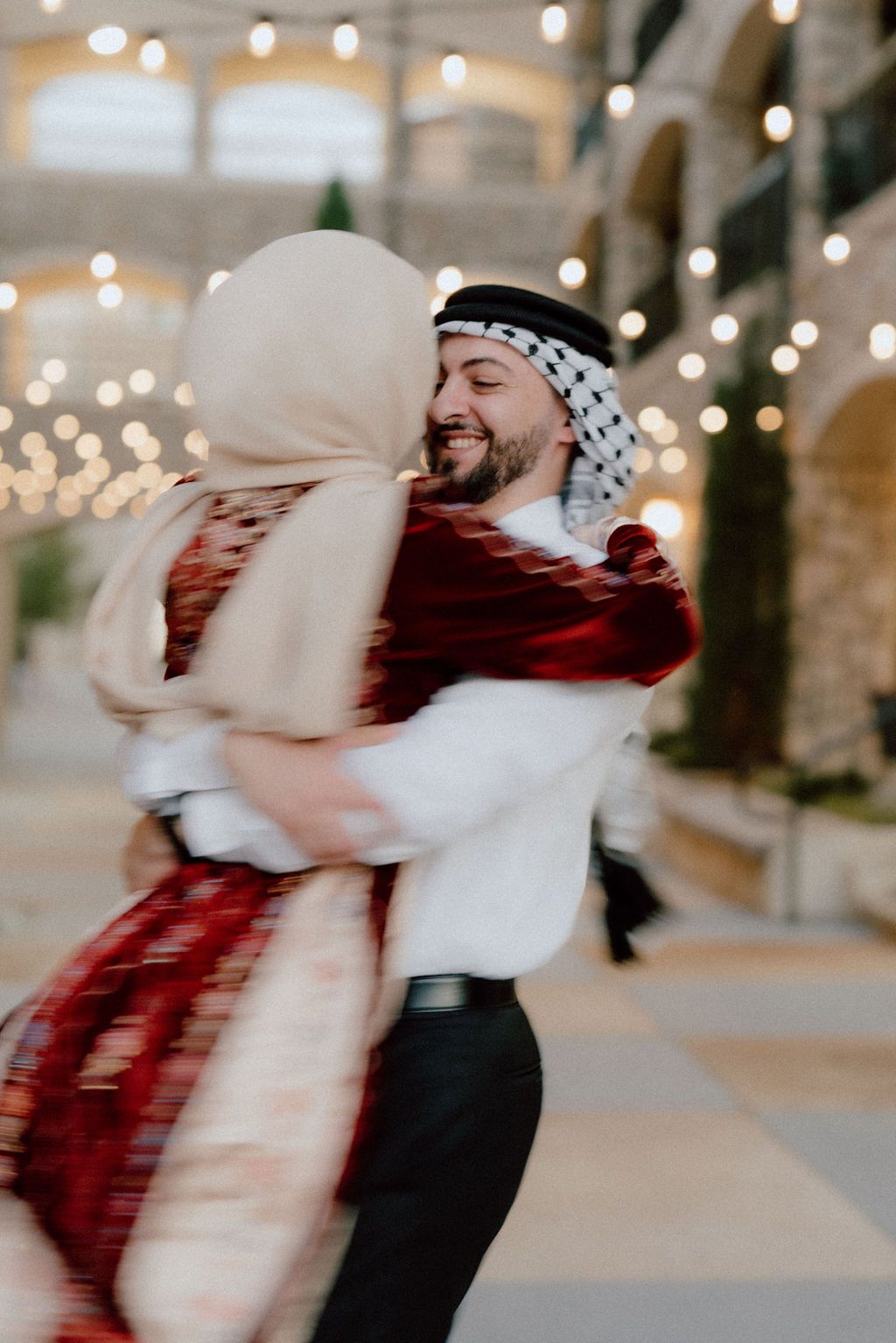 A joyful dancing couple in traditional Middle Eastern attire spinning under twinkling lights.