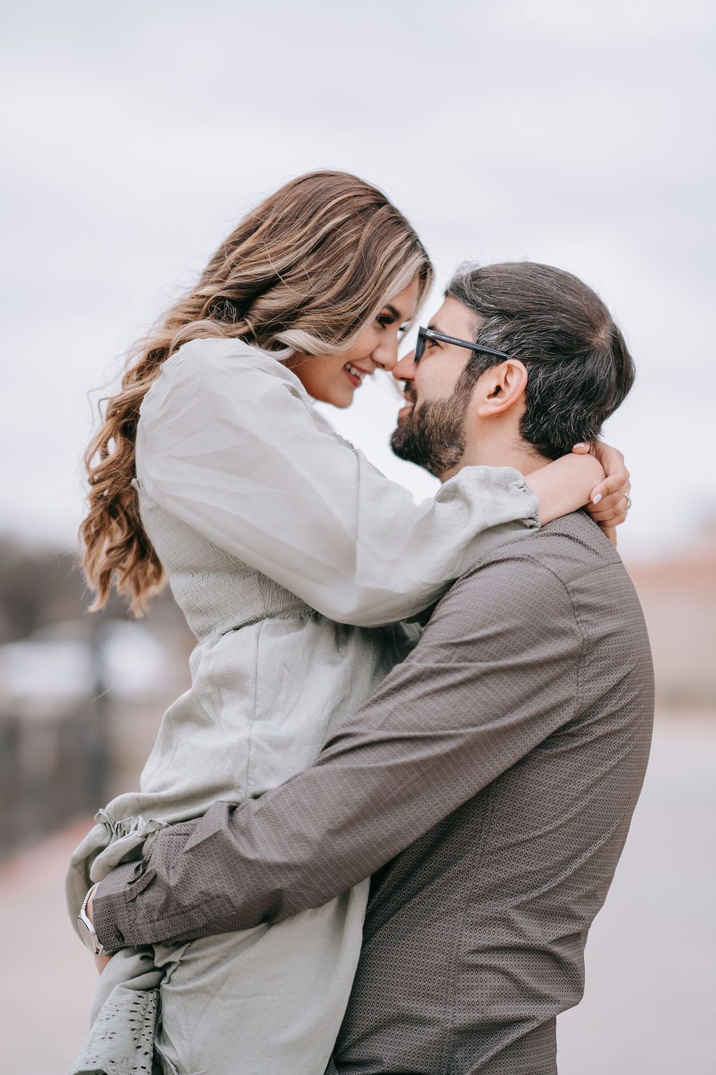 Intimate moment between couple sharing close embrace outdoors in casual attire.