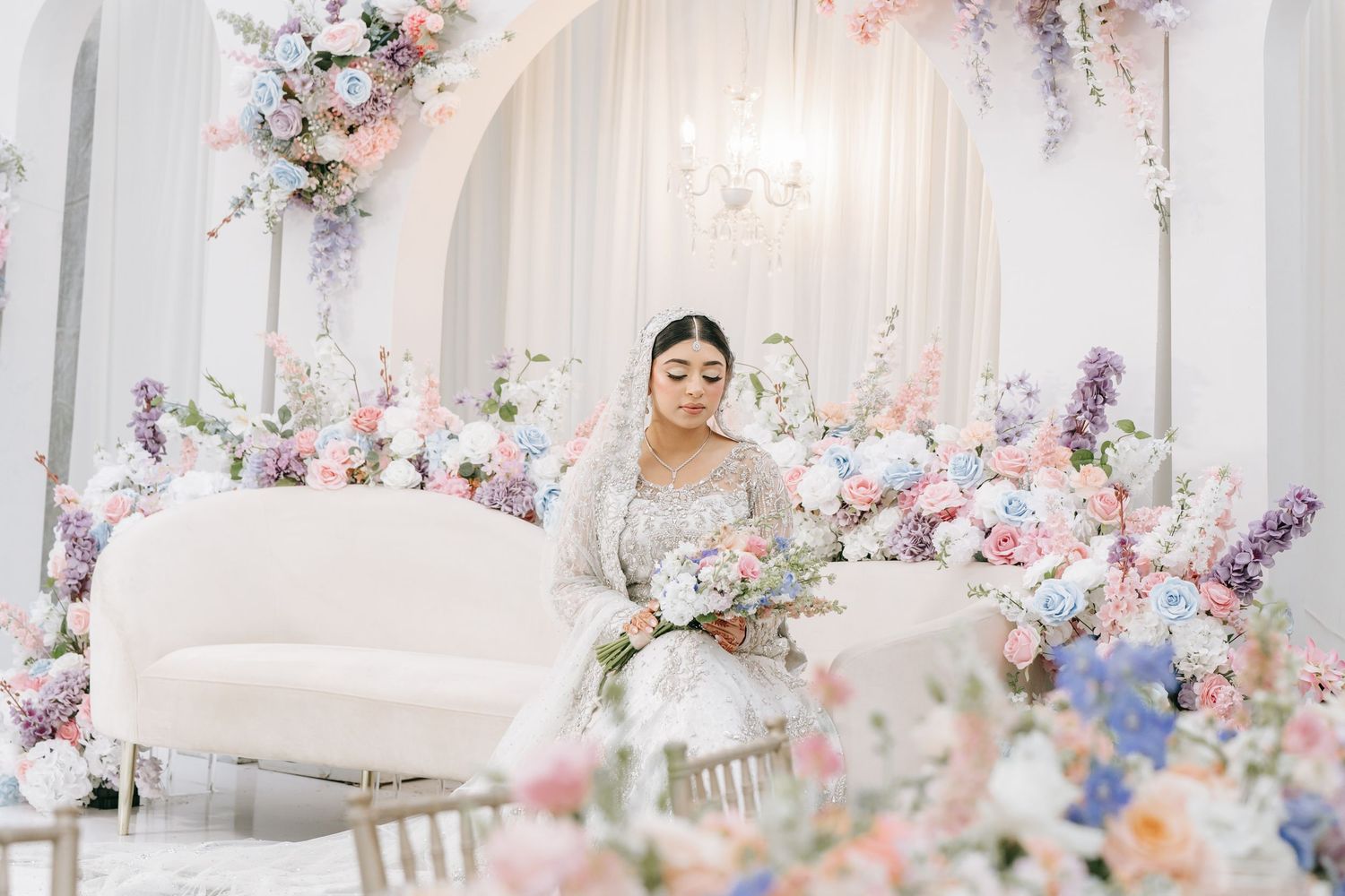 Elegant wedding reception venue decorated with pink and purple floral arrangements and white columns.