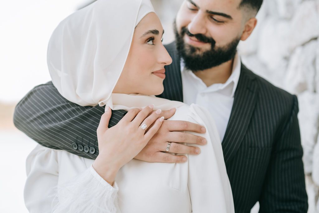 Tender embrace captured in sunlit moment featuring traditional Muslim wedding attire.