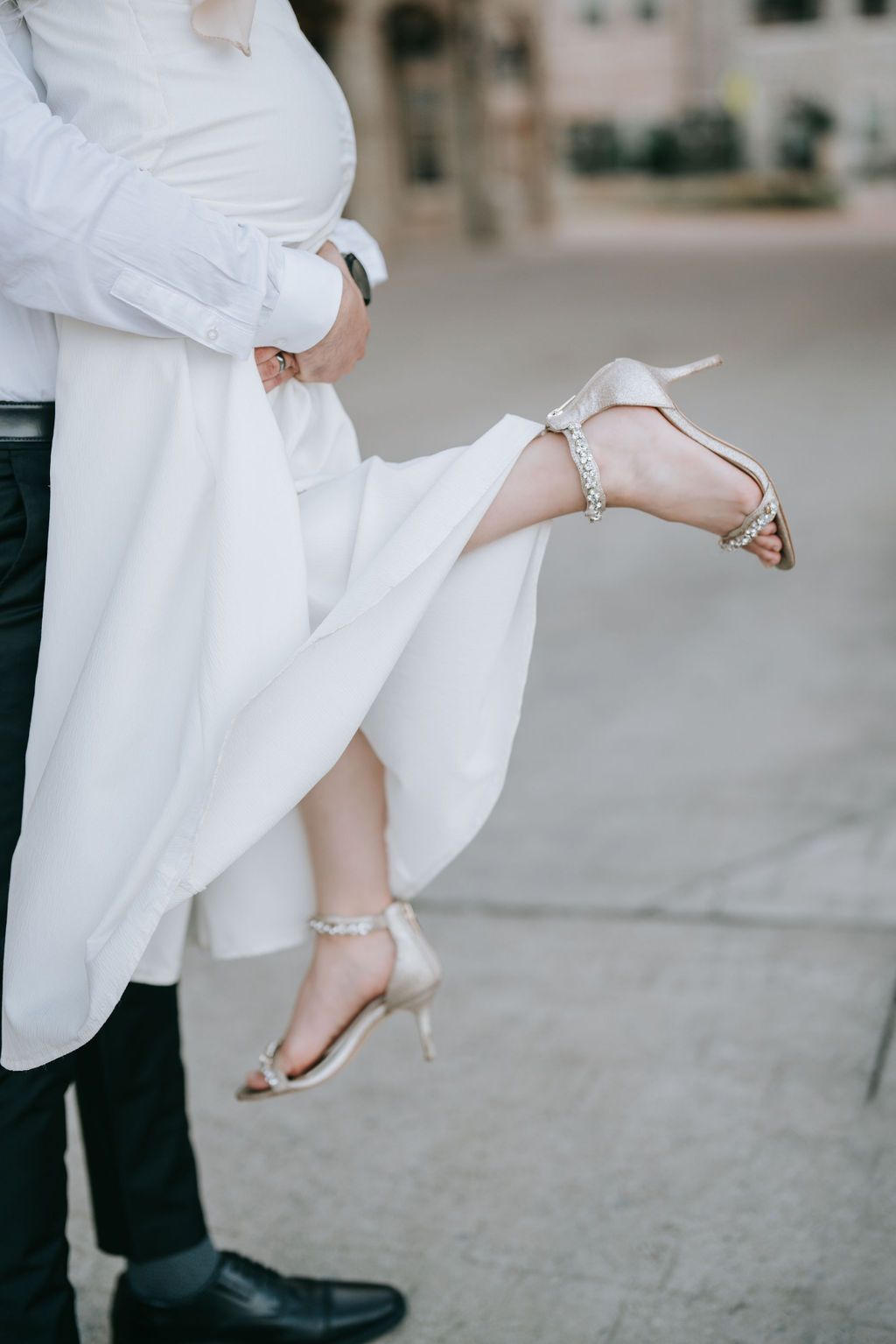 Detail shot of dancing feet, with a white dress and elegant bridal shoes in focus.