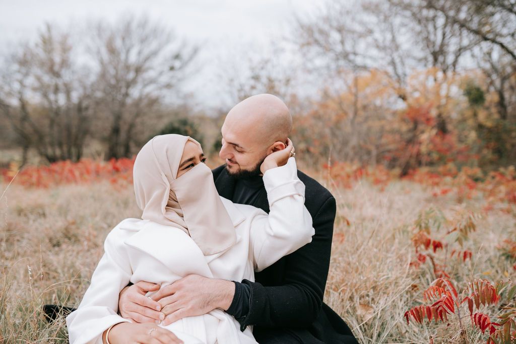 Intimate autumn portrait of couple in white attire amid fall foliage.