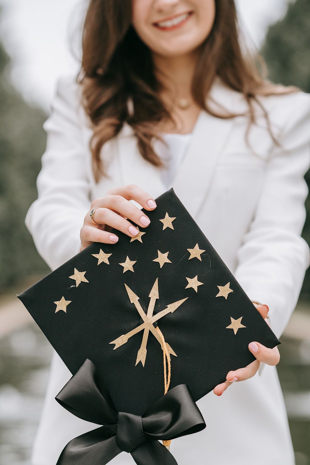 Decorated graduation cap featuring gold stars and bow against dark background.