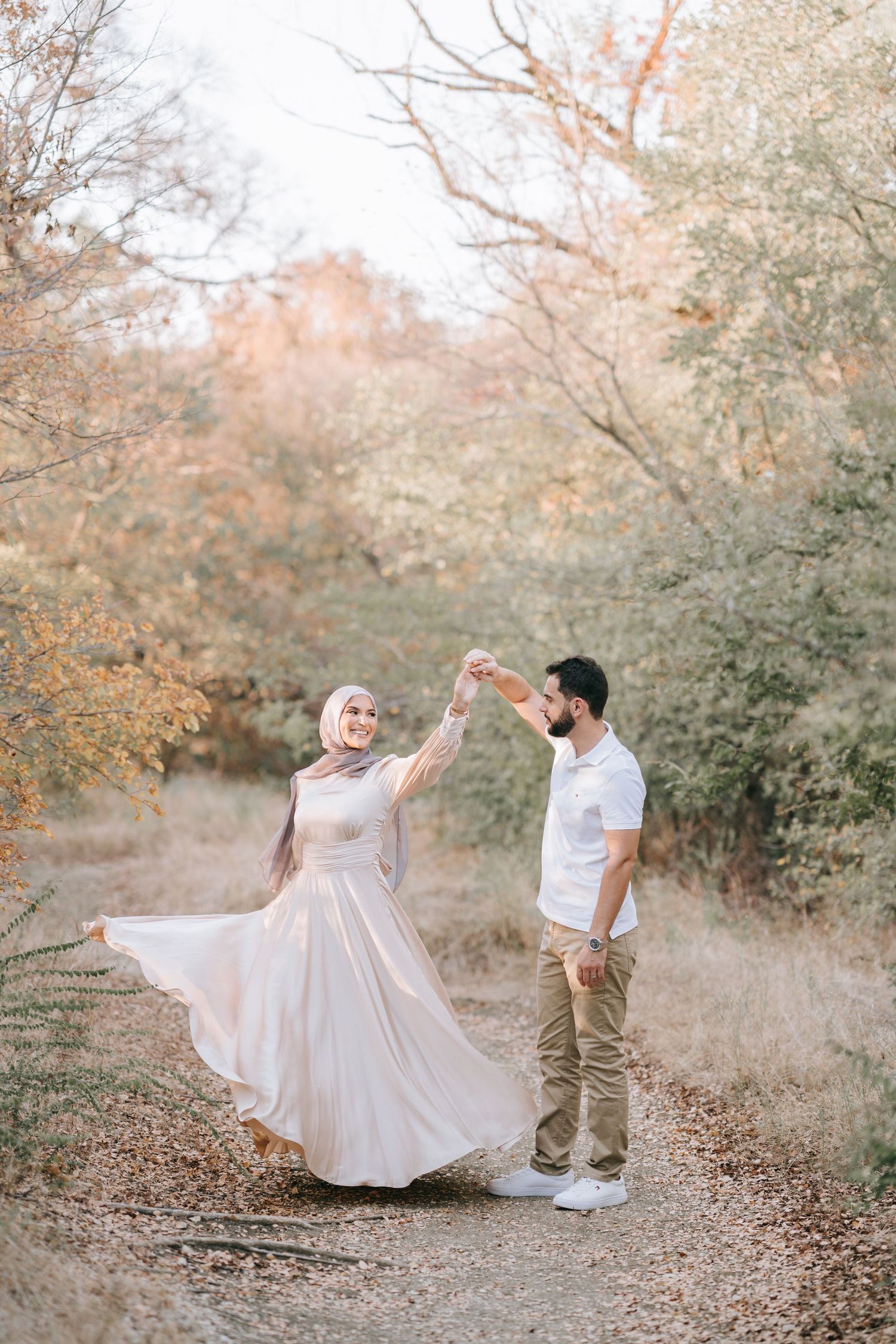 Bride and groom walking through golden field at sunset for outdoor Dallas wedding photoshoot.