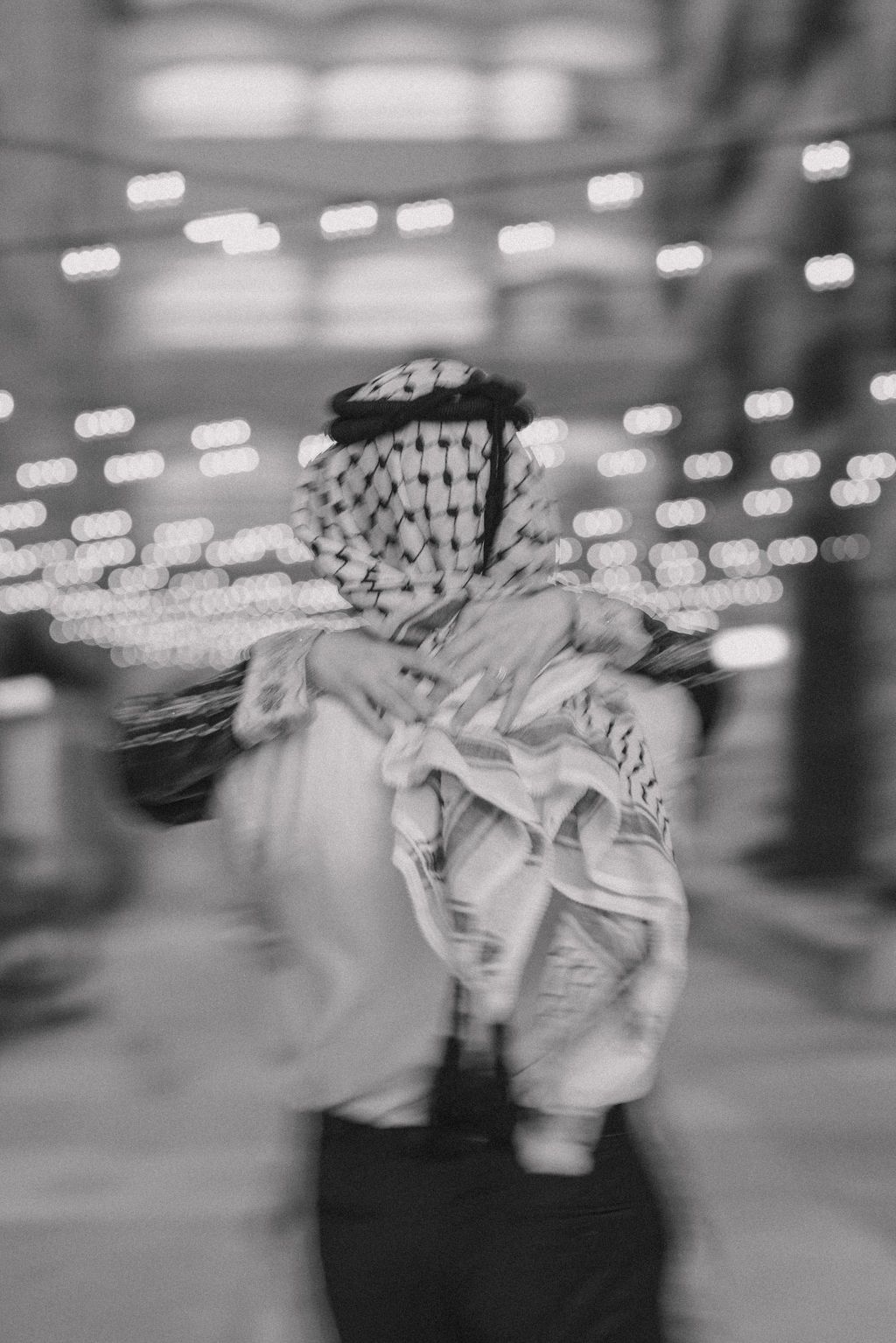 Motion-blurred black and white photo of someone in traditional Middle Eastern attire spinning in light.