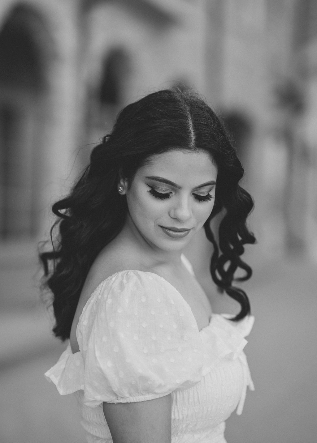 Portrait of woman in white off-shoulder dress with flowing dark hair.