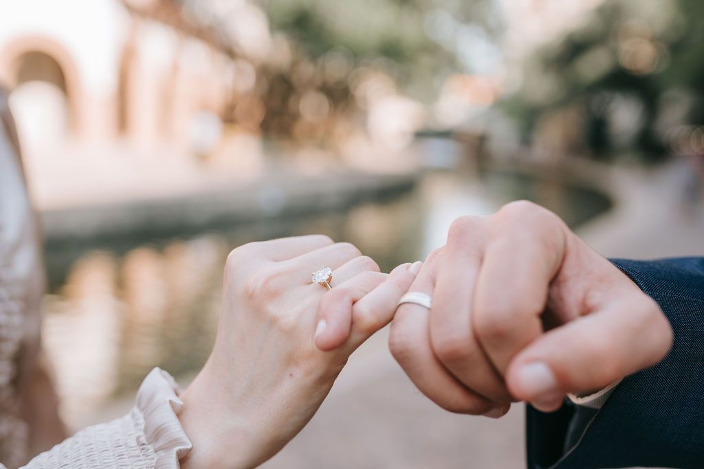 Close-up shot of two hands tenderly clasped together against a blurred background.